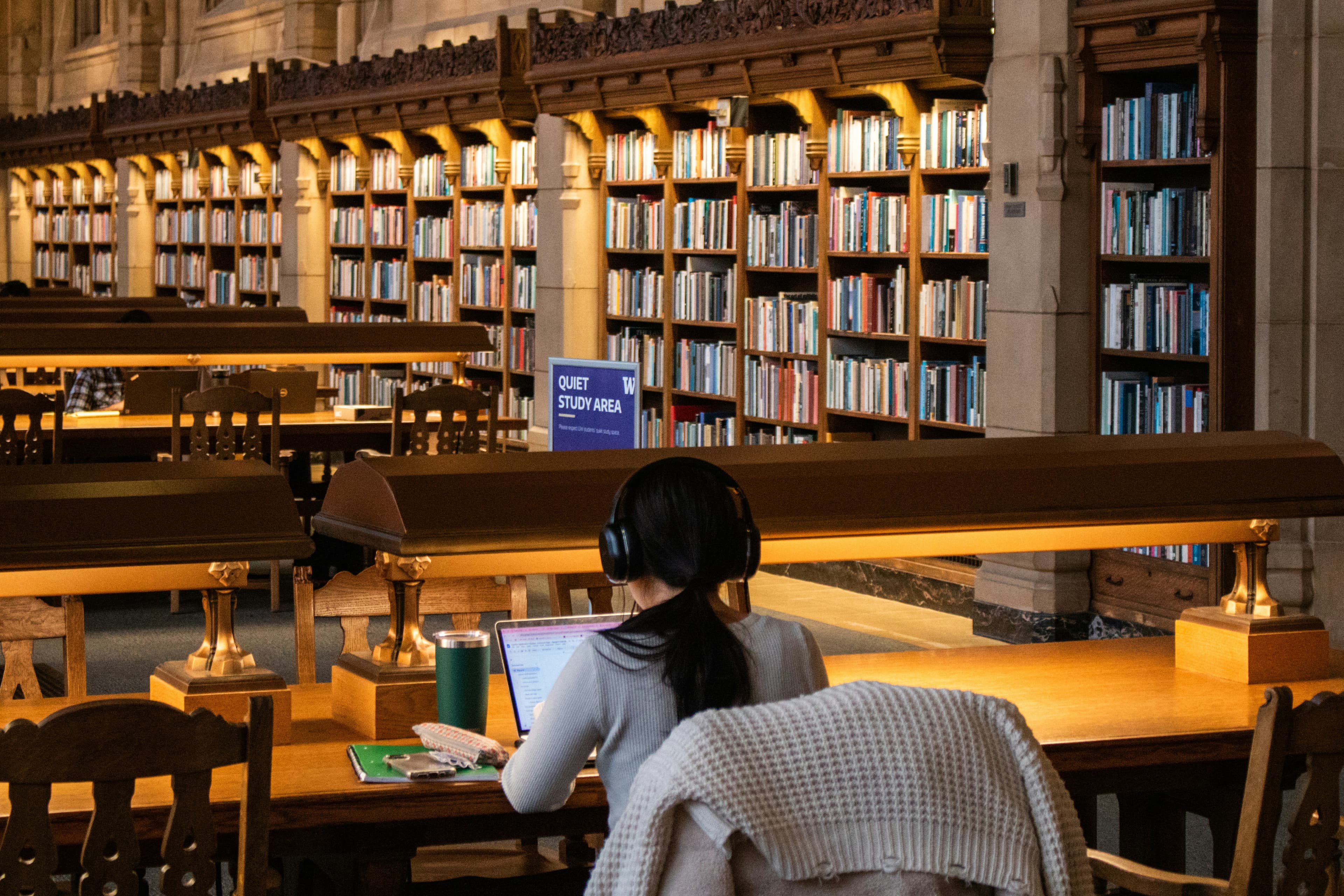 A student studying with books and a laptop in the University of Washington library